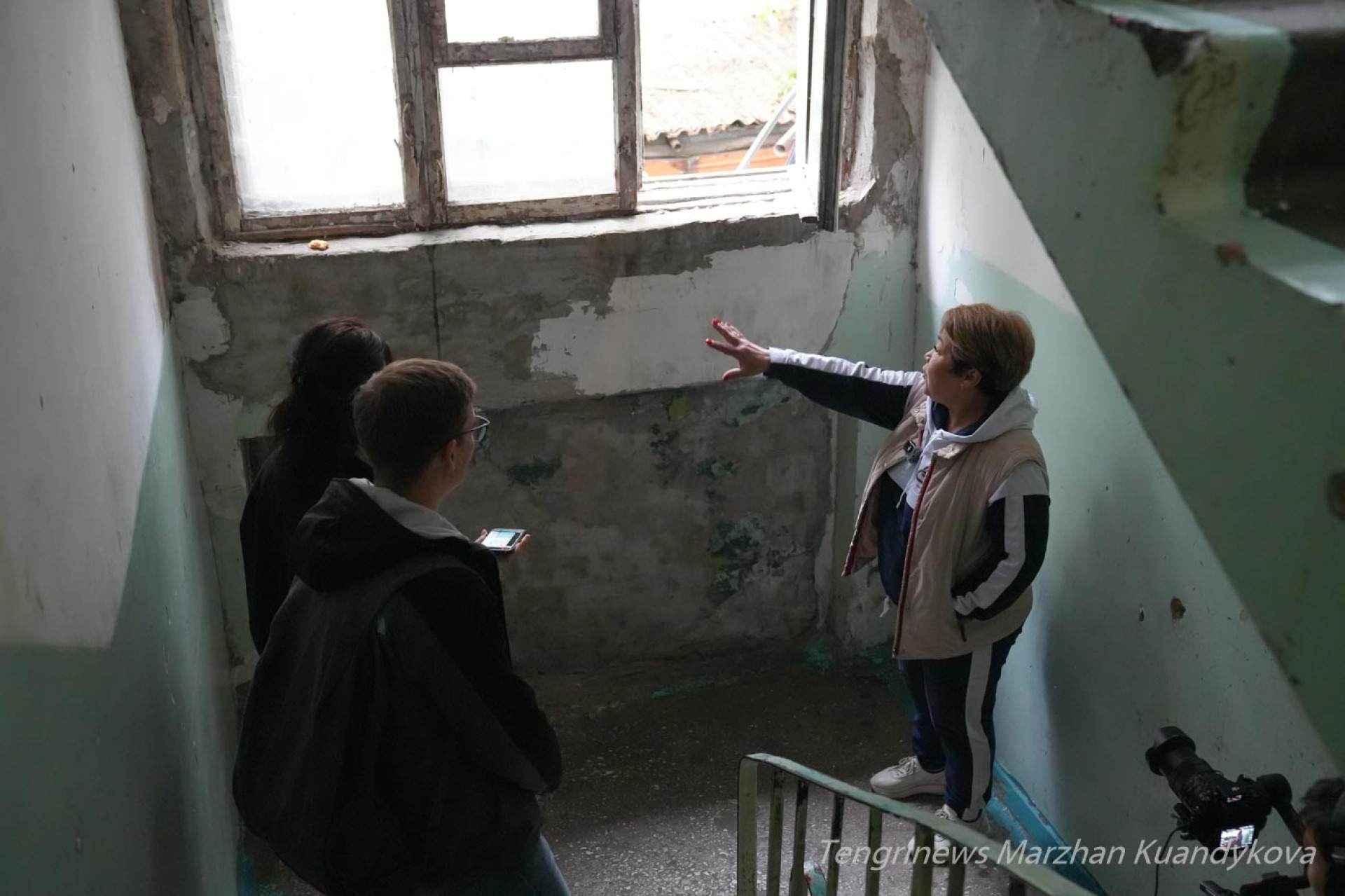 Гульбарам, старшая по дому, показывает облупившиеся стены аварийного общежития на Пастера в Астане